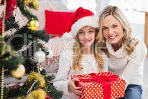 Festive mother and daughter beside christmas tree