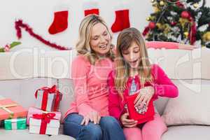 Little girl opening a gift at christmas with mother