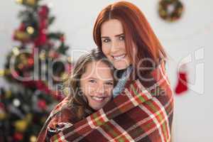 Festive mother and daughter wrapped in blanket
