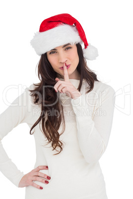 Festive brunette in santa hat keeping a secret