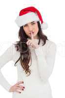 Festive brunette in santa hat keeping a secret