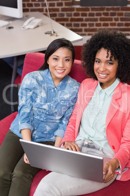 Casual colleagues using laptop on couch