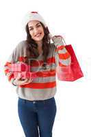 Smiling brunette holding gifts and showing shopping bag