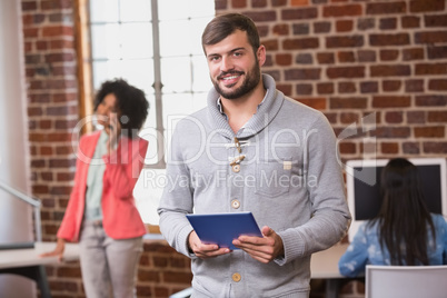 Man using digital tablet with colleague behind in office