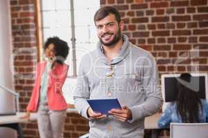 Man using digital tablet with colleague behind in office