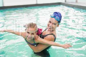 Cute little girl learning to swim with coach