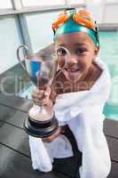 Cute little boy wrapped in towel with trophy poolside