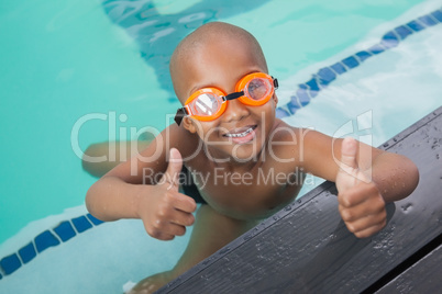 Cute little boy giving thumbs up at the pool