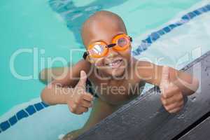 Cute little boy giving thumbs up at the pool