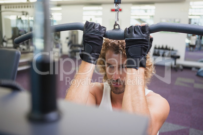 Young man exercising on a lat machine in gym