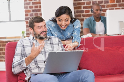 Casual colleagues using laptop on couch