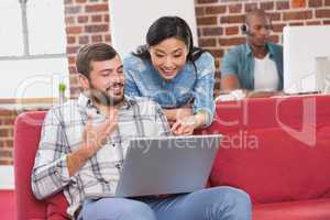 Casual colleagues using laptop on couch