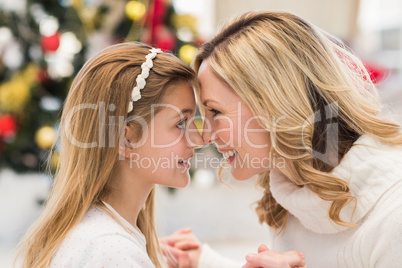 Festive mother and daughter beside christmas tree