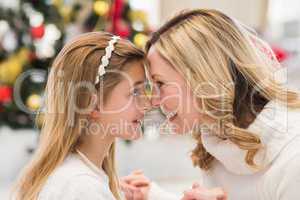 Festive mother and daughter beside christmas tree