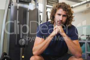 Serious handsome trainer sitting in gym