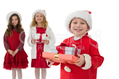 Festive little siblings smiling at camera holding gifts