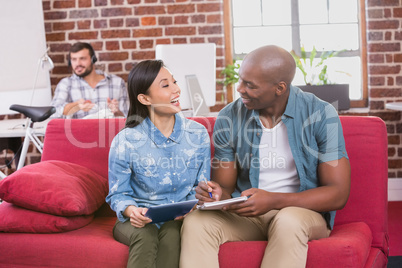 Casual colleagues using digital tablet on couch