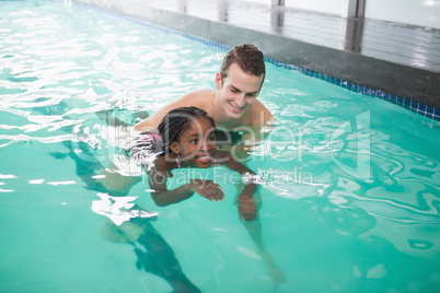 Cute little girl learning to swim with coach