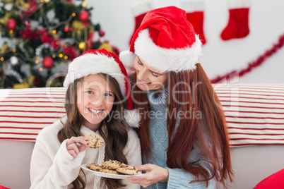 Festive mother and daughter on the couch with cookies