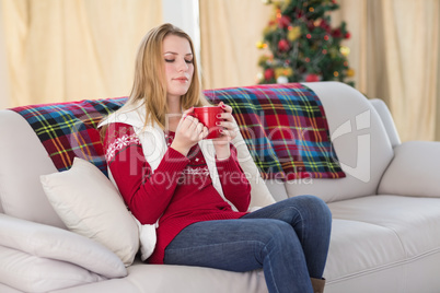 Cheerful cute blonde sitting on couch holding mug