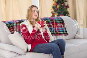 Cheerful cute blonde sitting on couch holding mug