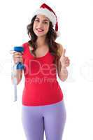 Festive fit brunette holding measuring tape and dumbbell