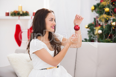 Happy brunette holding a red bauble at christmas