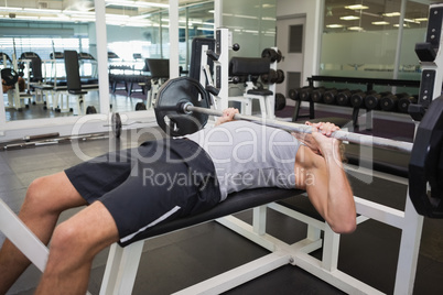 Muscular man lifting barbell in gym