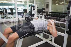 Muscular man lifting barbell in gym