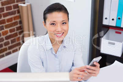 Smiling female executive text messaging in office