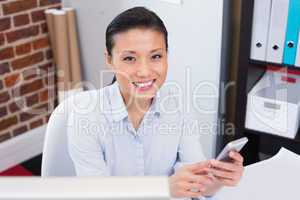 Smiling female executive text messaging in office