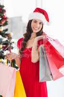 Smiling brunette in red dress holding shopping bags
