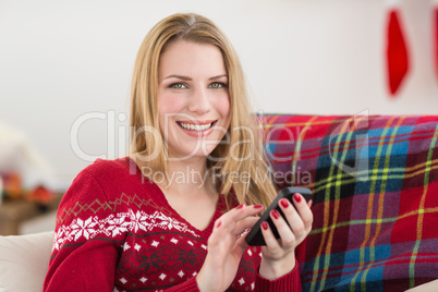 Pretty blonde sitting on the couch texting on the phone