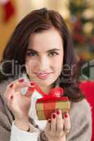 Smiling brunette opening a gift on christmas day