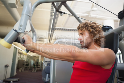 Side view of man working on fitness machine at gym