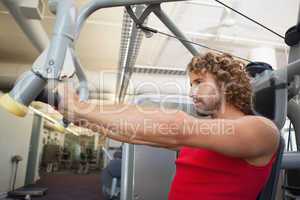 Side view of man working on fitness machine at gym