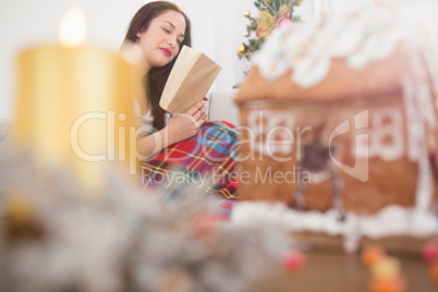 Peaceful brunette reading on the couch with cover