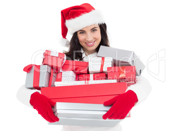 Smiling brunette in santa hat holding stack of presents