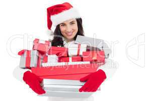 Smiling brunette in santa hat holding stack of presents