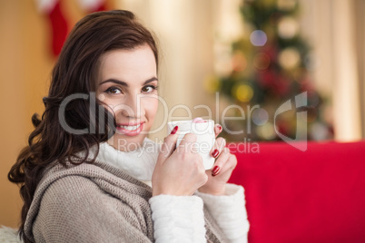 Smiling brunette holding a mug of hot chocolate at christmas