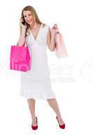 Happy blonde holding shopping bags and talking on phone