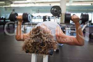 Young man exercising with dumbbells in gym