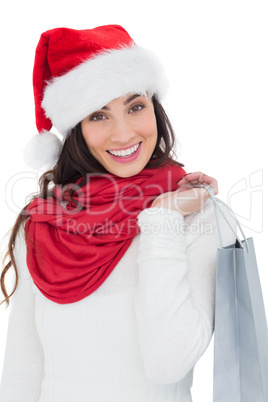 Festive brunette in winter wear holding shopping bag