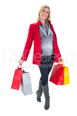 Happy blonde in winter clothes holding shopping bags