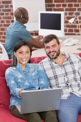 Casual colleagues using laptop on couch