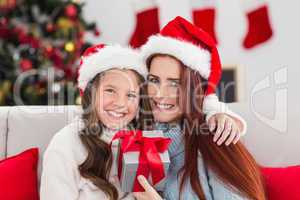 Festive mother and daughter holding christmas present