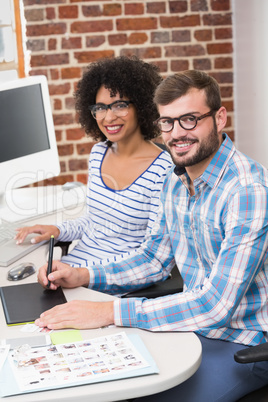 Smiling photo editors using digitizer in office Smiling photo editors using digitizer in office