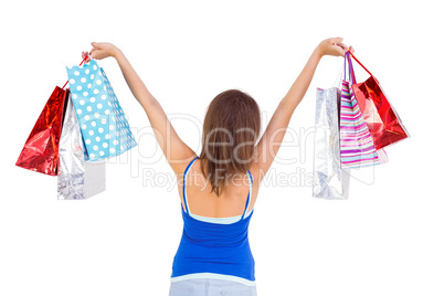 Rear view of a brunette woman raising shopping bags
