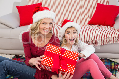 Festive mother and daughter smiling at camera with gifts