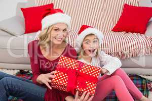 Festive mother and daughter smiling at camera with gifts